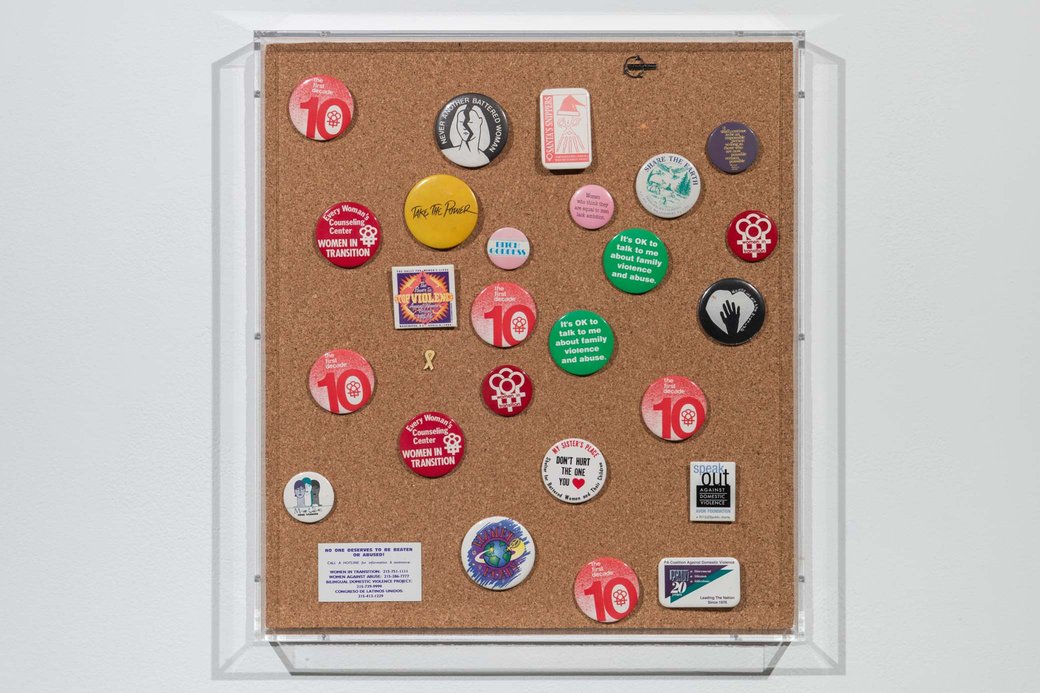 A collection of a dozen or so buttons with various statements against gendered violence, for example, “take the power.”