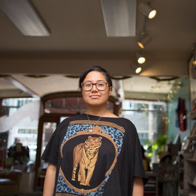 Dorothy Santos stands in the middle of a book shop with an archway above them, looking directly into the camera.