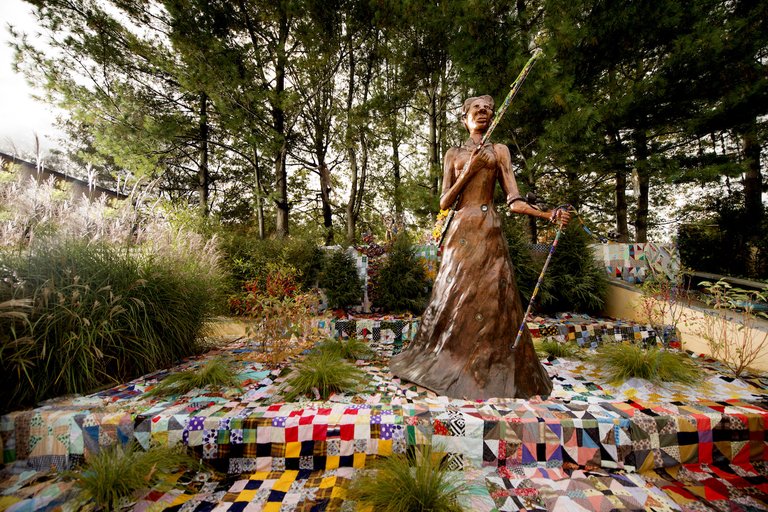 Joyce J. Scott, “Araminta With Rifle And Vèvè” (2017), painted milled foam with found objects and milled foam rifle with blown glass and mixed media appliqués, beaded staff, dimensions variable (image courtesy Goya Contemporary Gallery, Baltimore, MD, pho