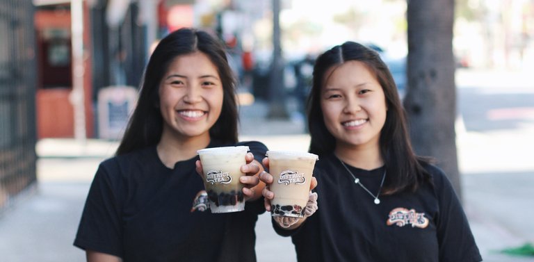 Photograph of CCA student Mickie Lau and her sister Rachel Lau holding bubble tea drinks.