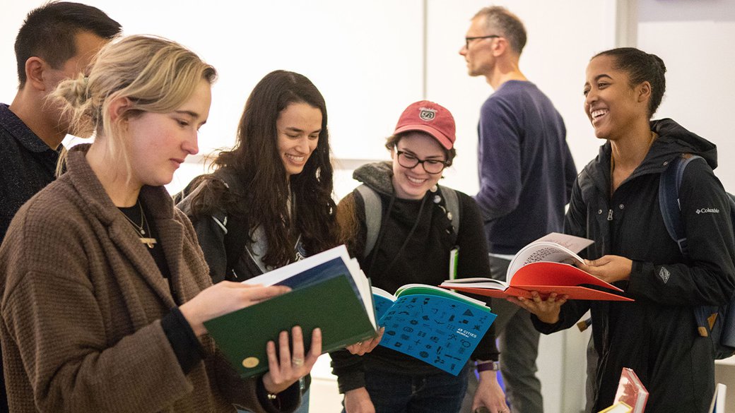 A group of students look through books after a speaking event.