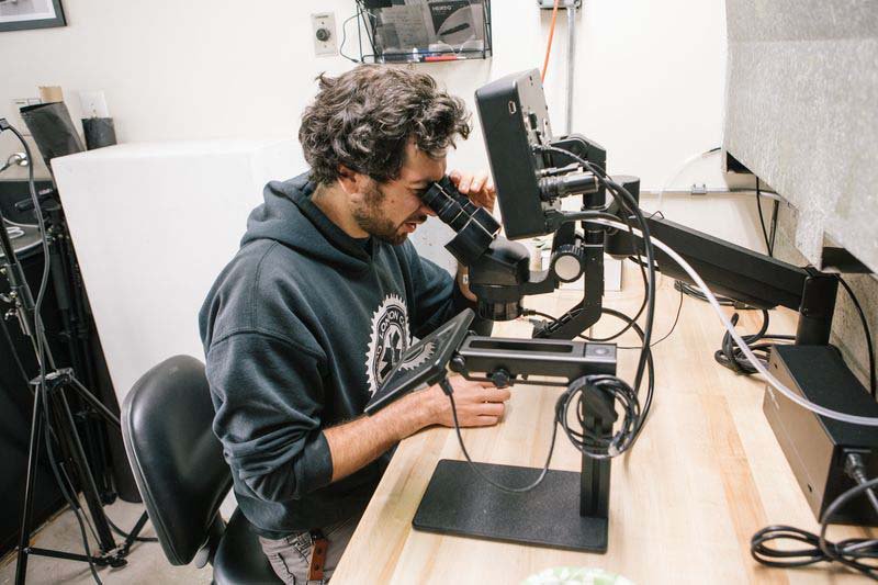 Jewelry and Metal working student examining and carving their jewelry
