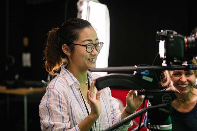 BFA Film student works with teacher to review video takes in green screen film cage