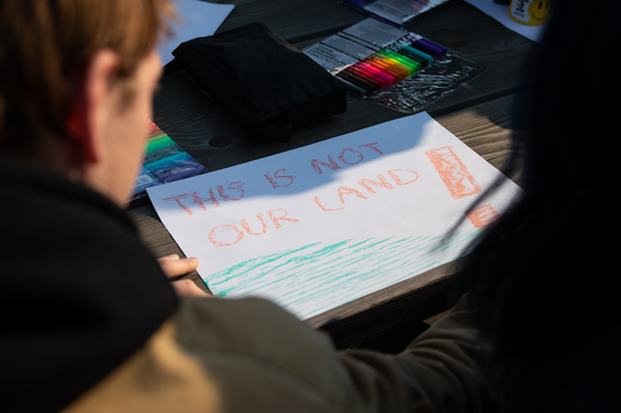 Students working on a sign that says, "This is not our land!"