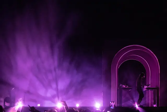 Wide-angle shot of Flume on stage awash in purple smoke