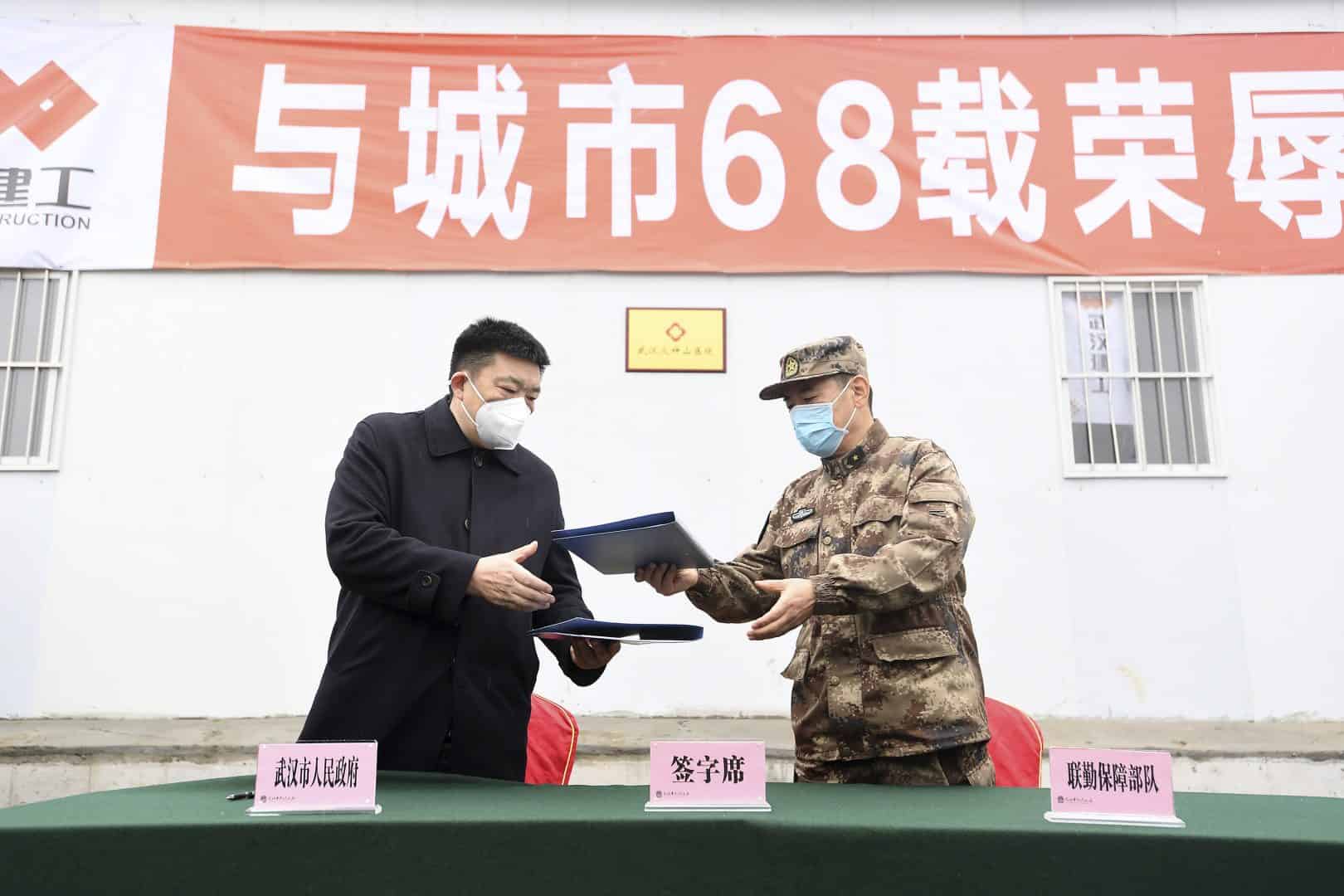 Zhou Xianwang, left, the mayor of Wuhan, exchanges documents with Bai Zhongbin, right, deputy commander-in-chief of China’s People’s Liberation Army (PLA) Joint Logistic Support Force, during a handover ceremony at the Huoshenshan temporary field hospital (AP)