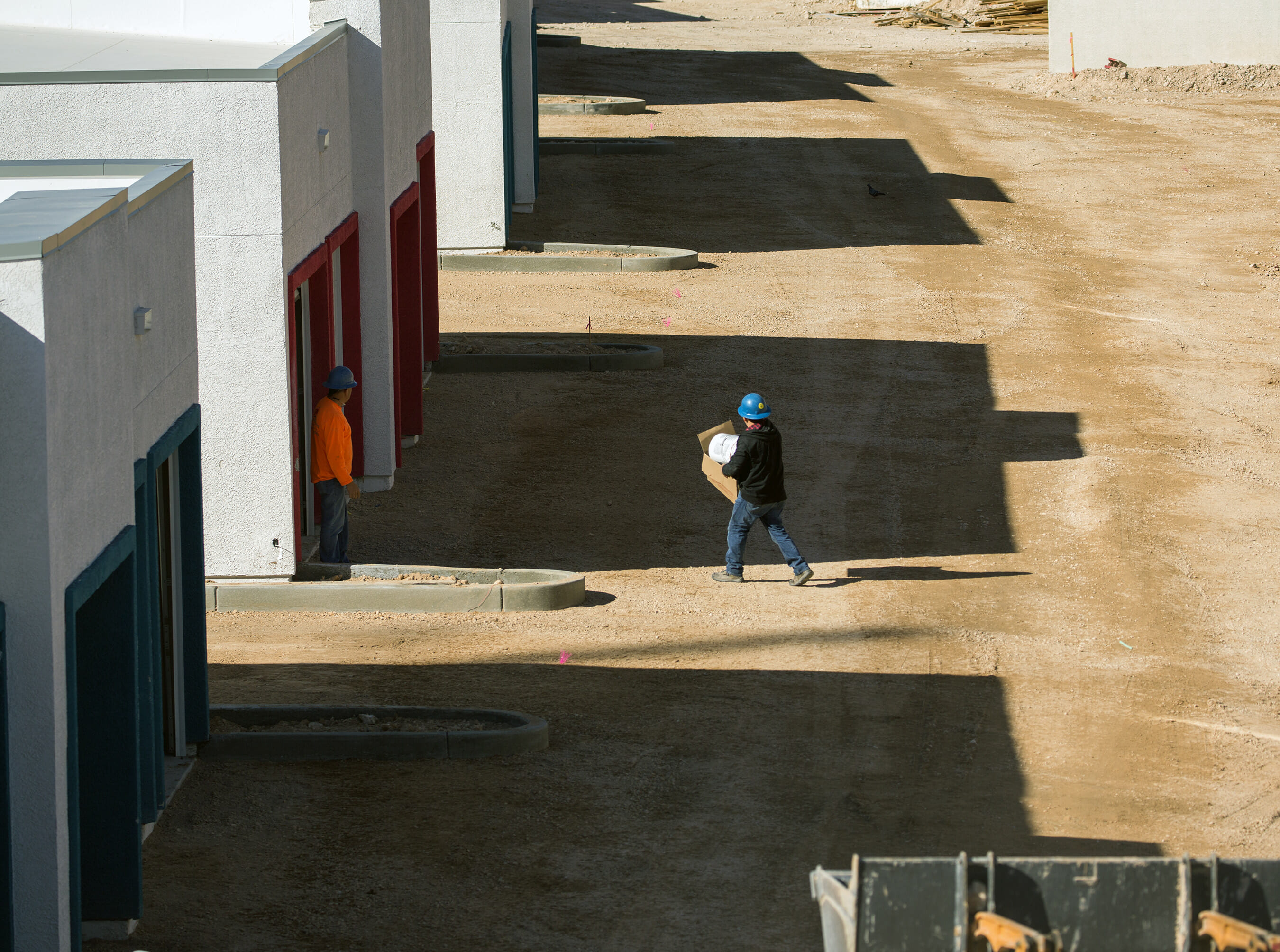 A workman walking towards an apartment building under construction