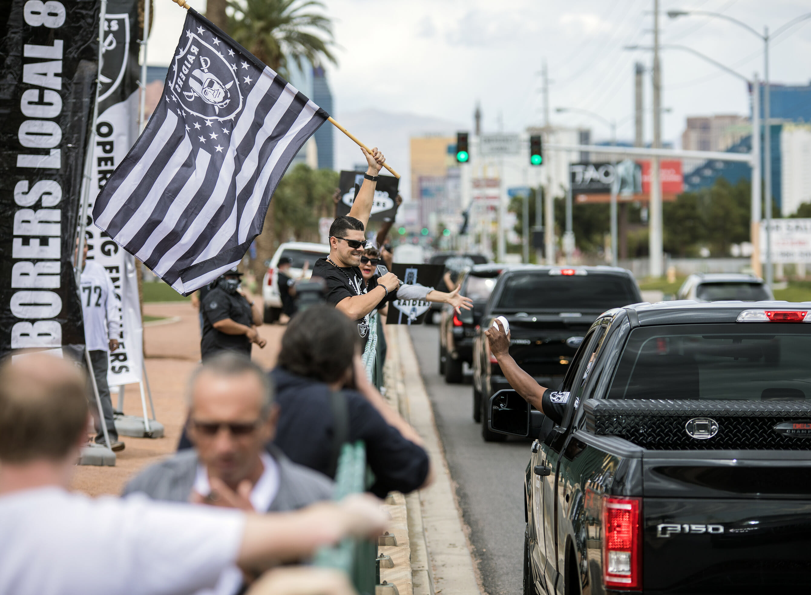 A man waiving a Raiders flag on a sidewalk