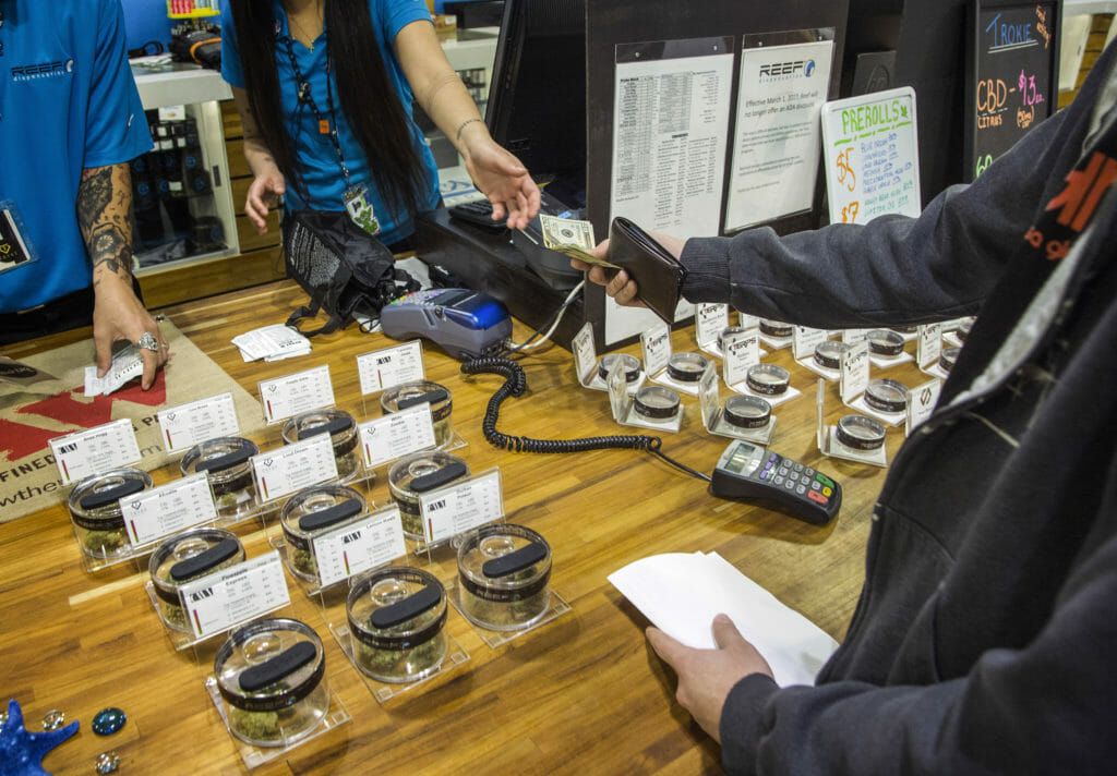 A customer and retailer exchanging money at a cannabis retailer