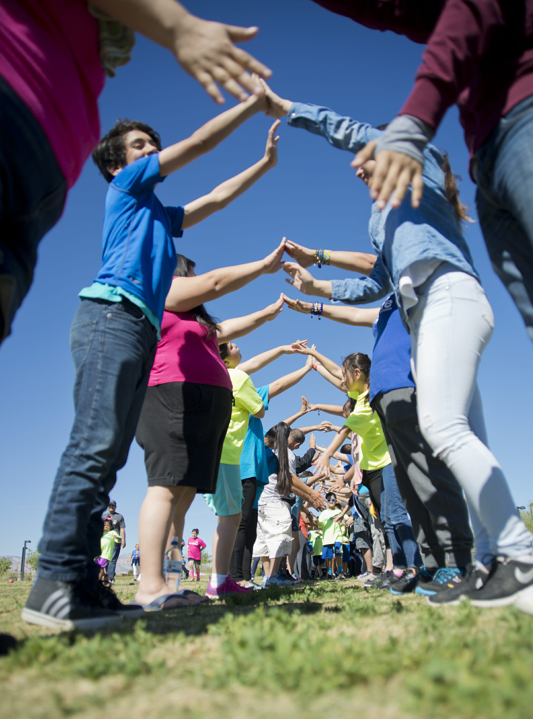 A group of adults holding hands to create a tunnel for kids to run through