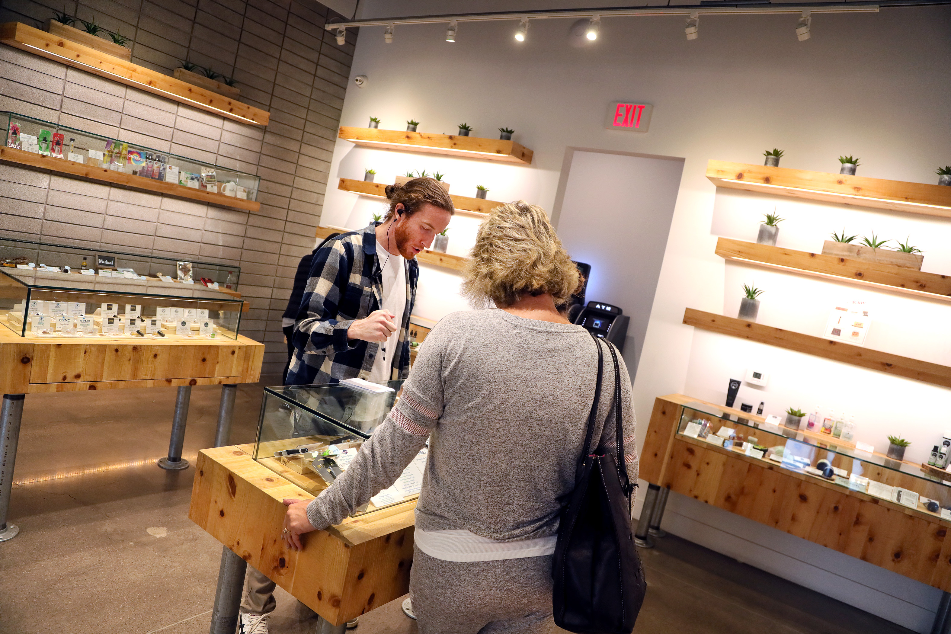 Patient advisor Regan Fueget explains marijuana products on display to a customer at the+source dispensary in Henderson