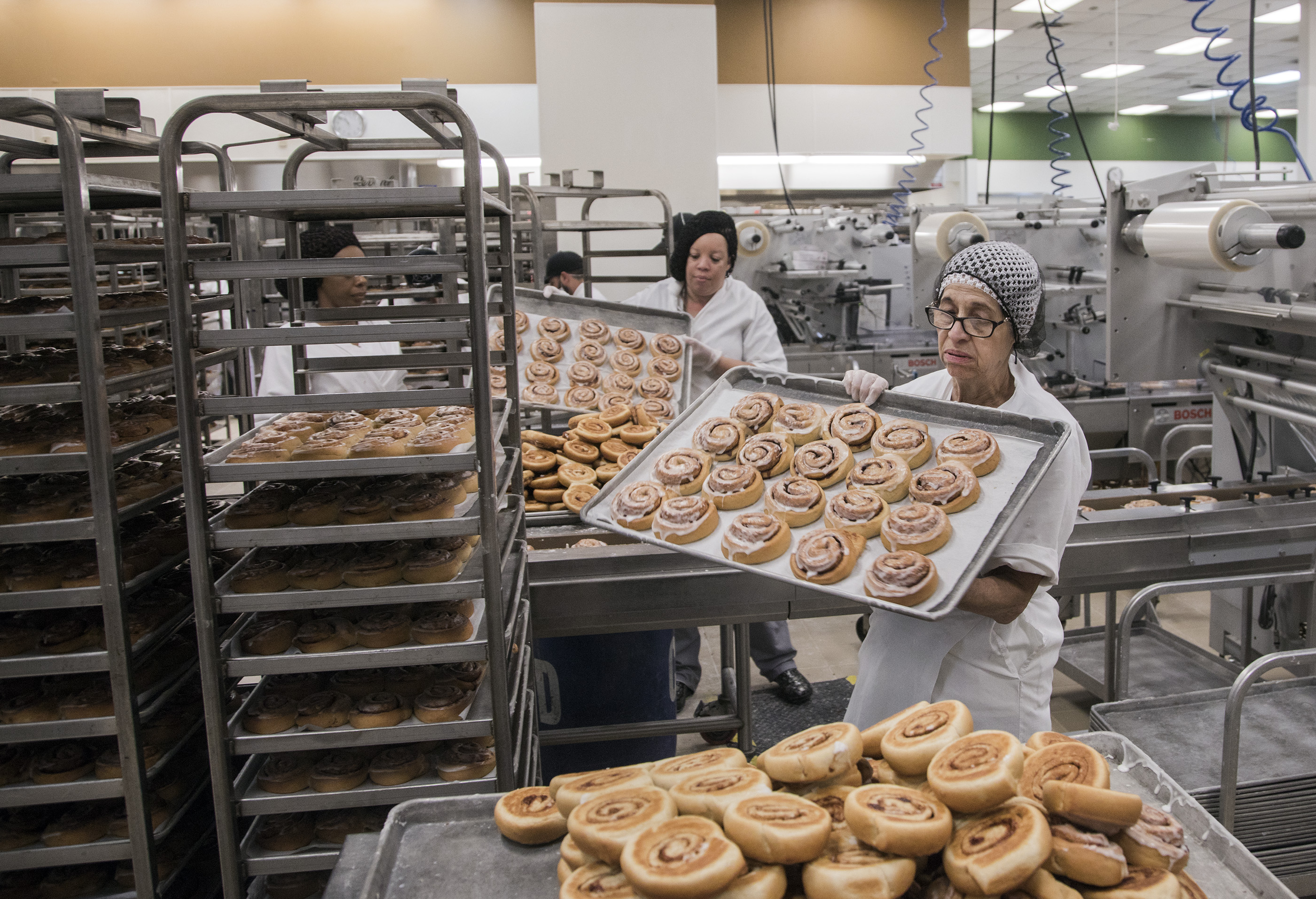 Food service personnel remove cinnamon rolls from trays at the Clark County School District Central Kitchen