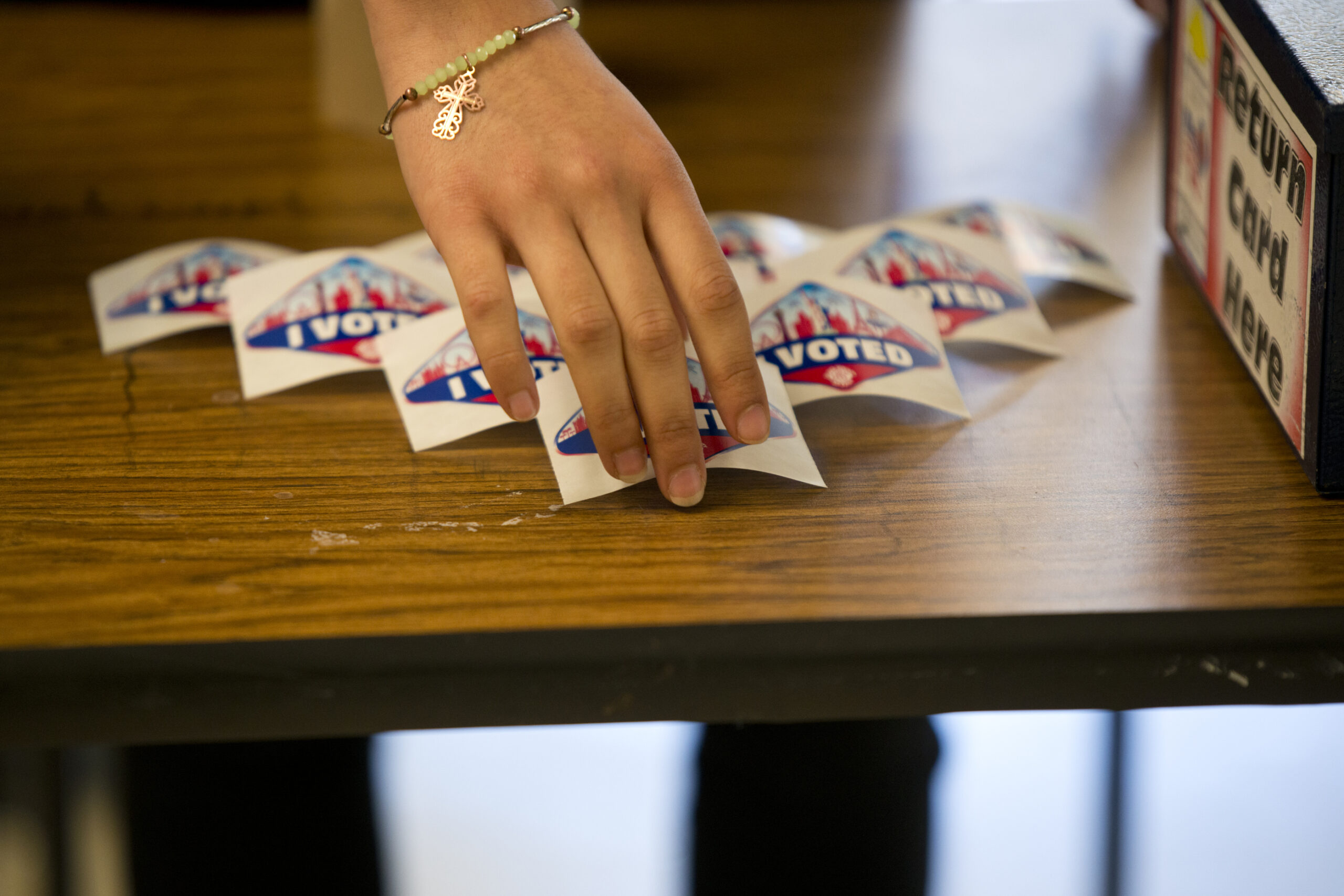 A hand arranging "I voted" stickers on a table