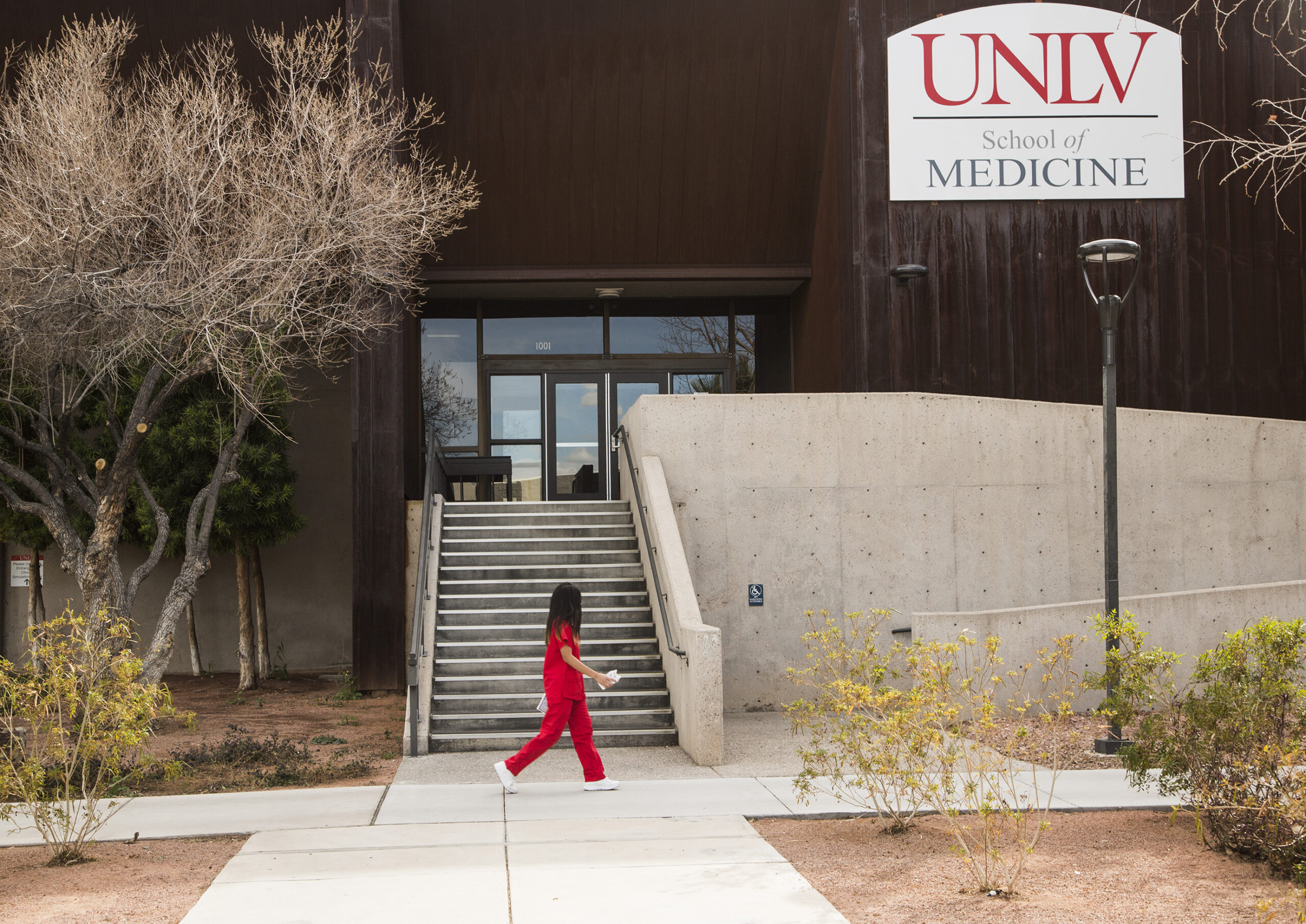 A student walking in front of the UNLV School of Medicine building