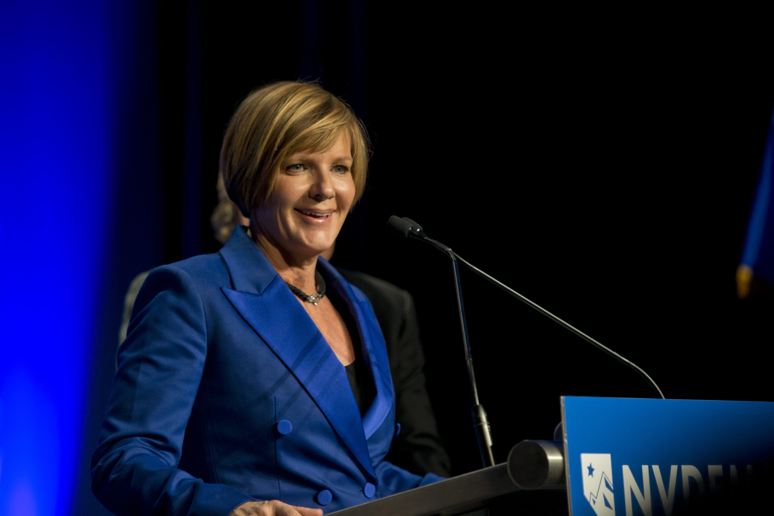 Susie Lee in a blue suit giving a speech