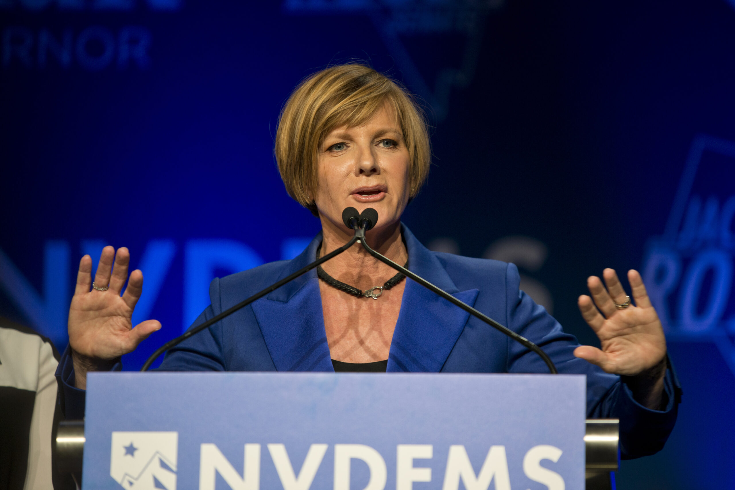 Susie Lee at a podium wearing a blue shirt