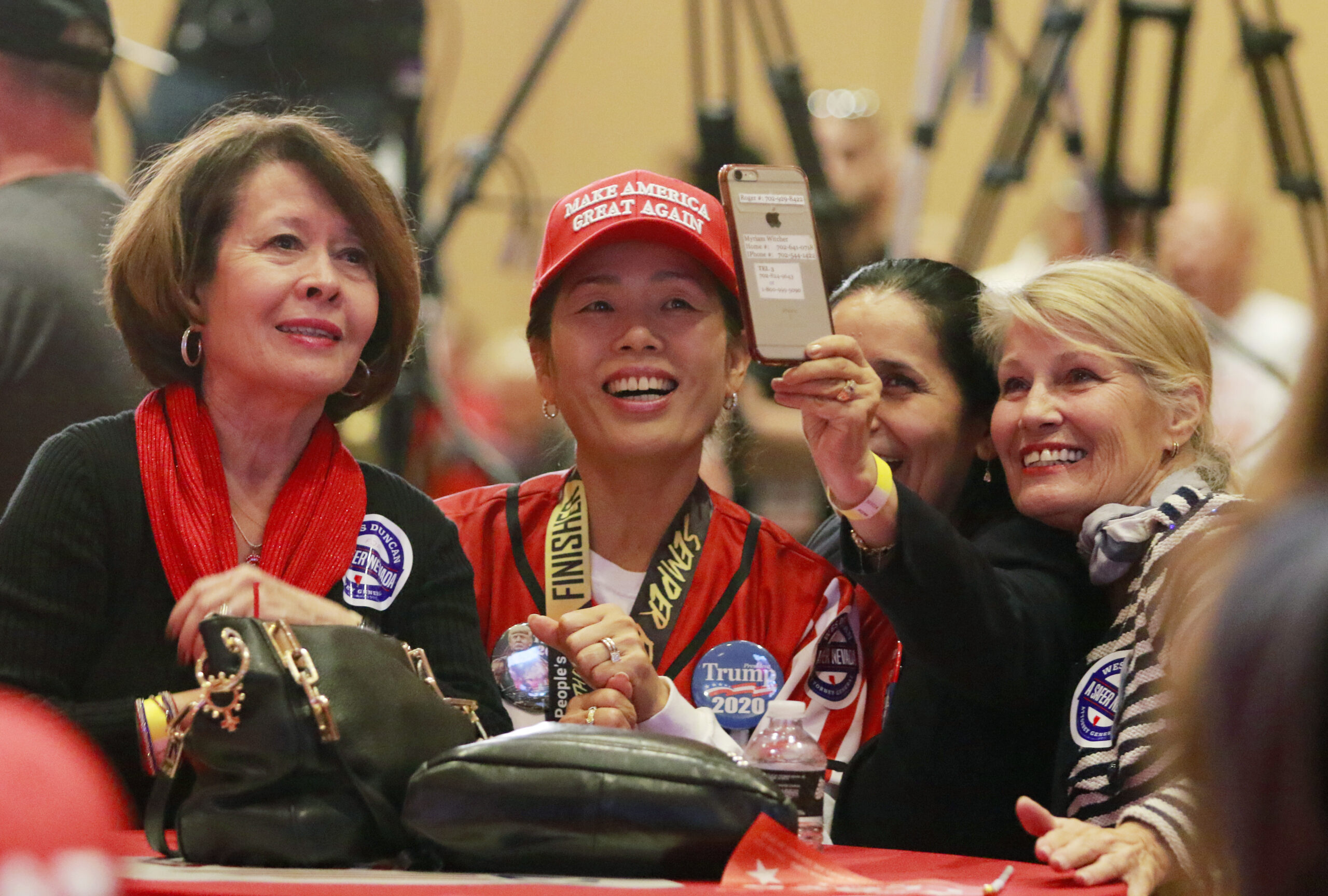 Friends Martha Kimpel, far left, and Sosoo Lee-Dunn, left, participate in a video phone call during a GOP Election Night Watch Party prior to results being announced