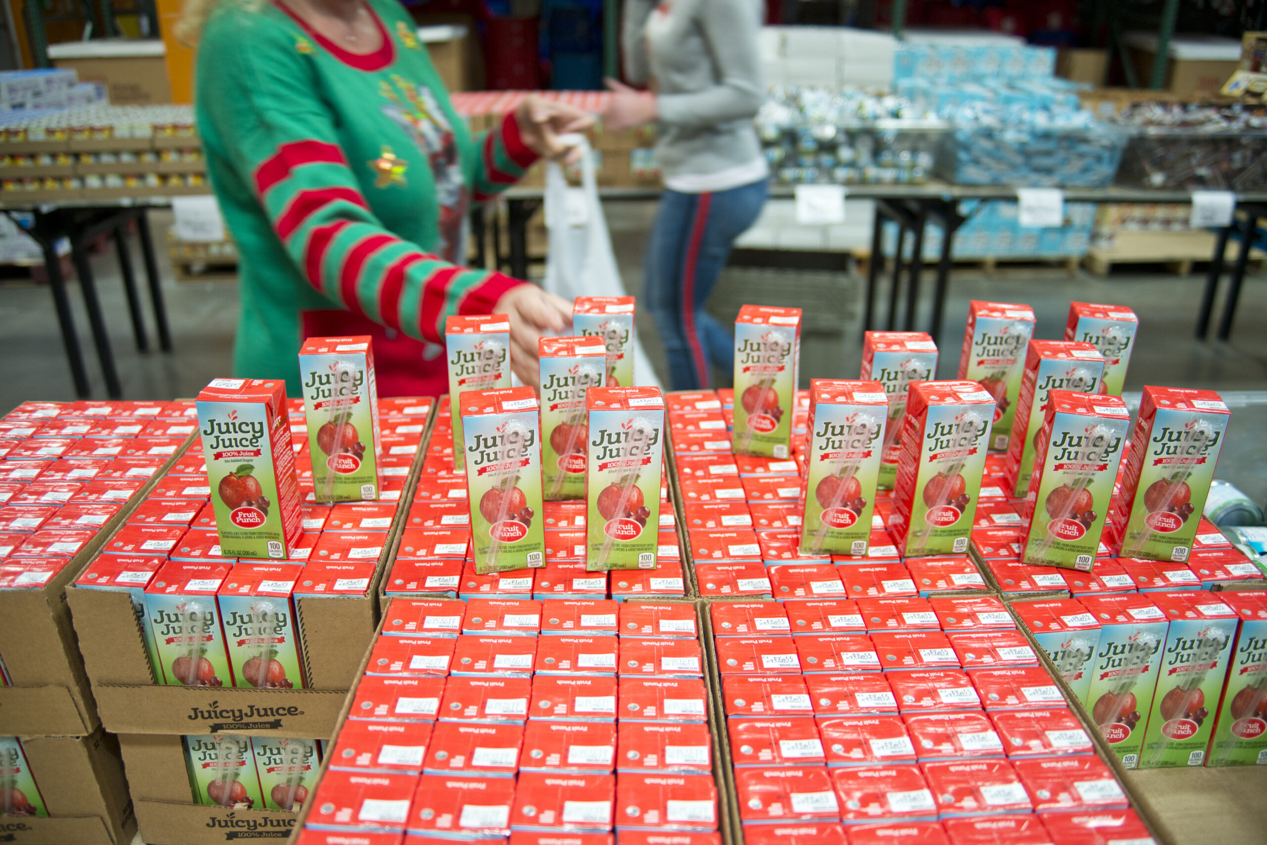 A worker in a holiday sweater standing in front of juice boxes