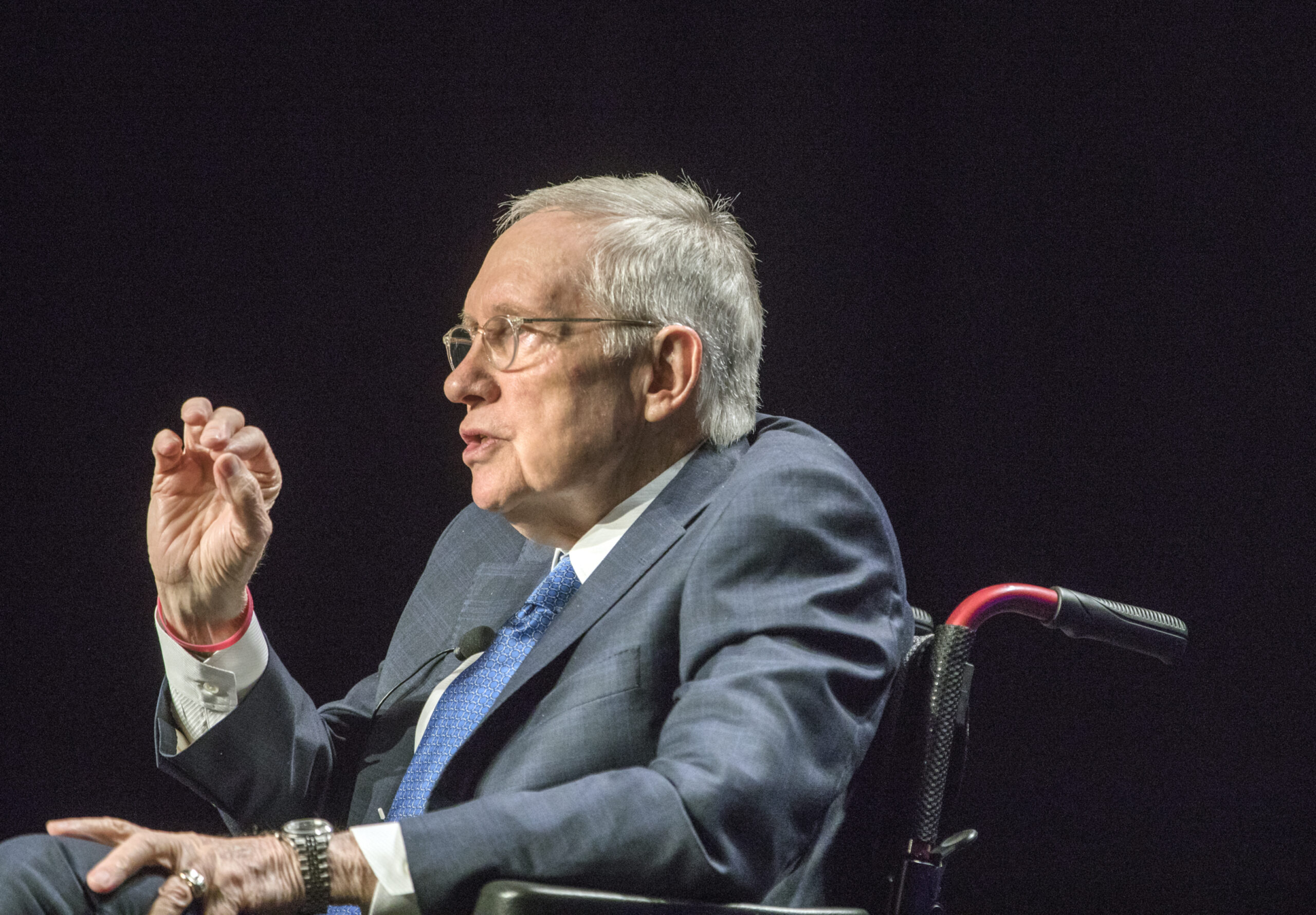 Harry Reid seated wearing a gray sportcoat and blue tie