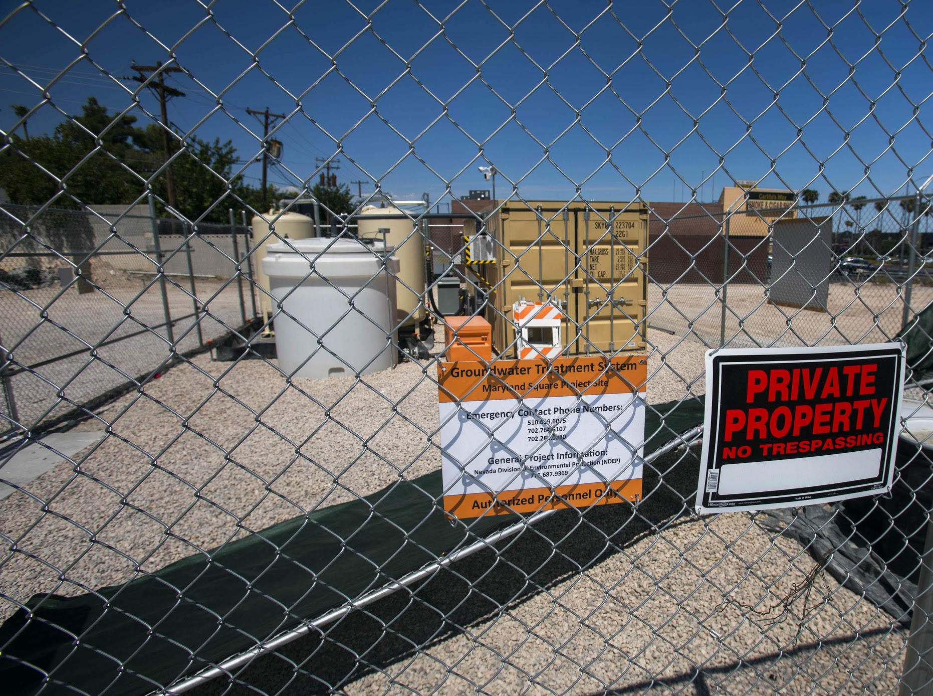 A private property sign on a chain link fence in front of items at the former site of a dry cleaner in Maryland Square