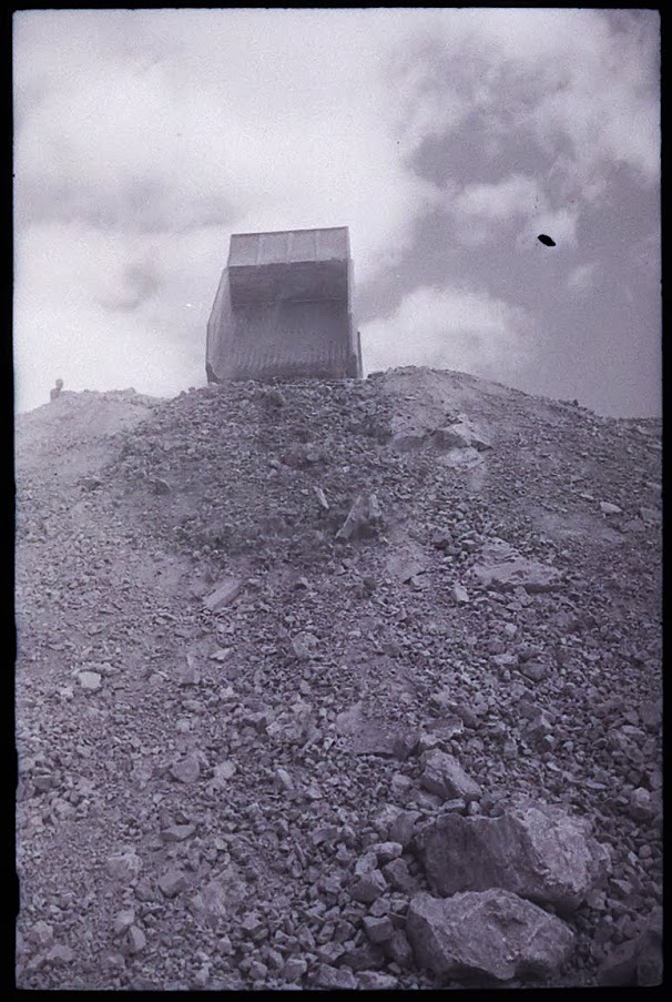 a dump truck dumps dirt into a mound