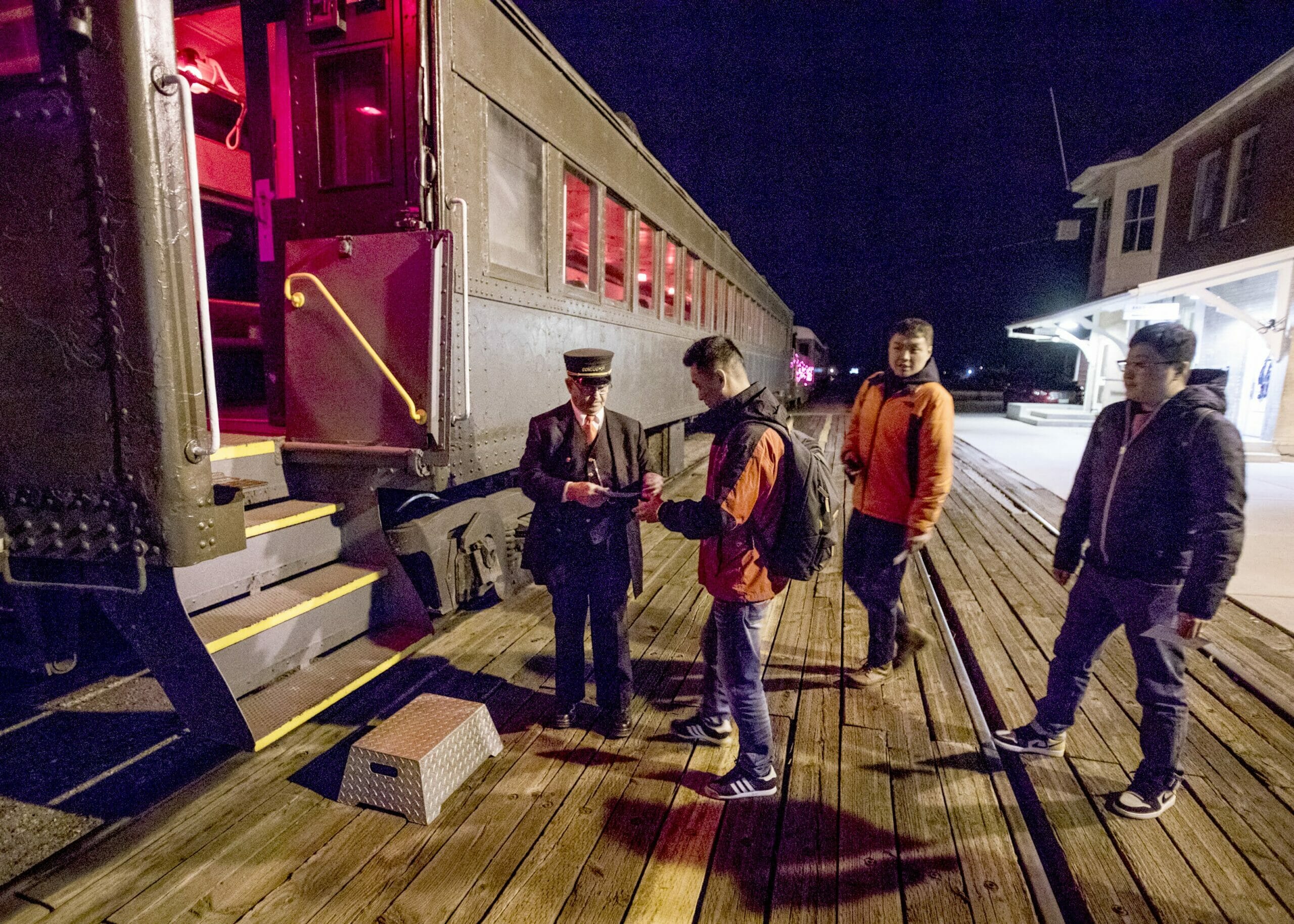 A train with a ticket taker and three passengers in line to board