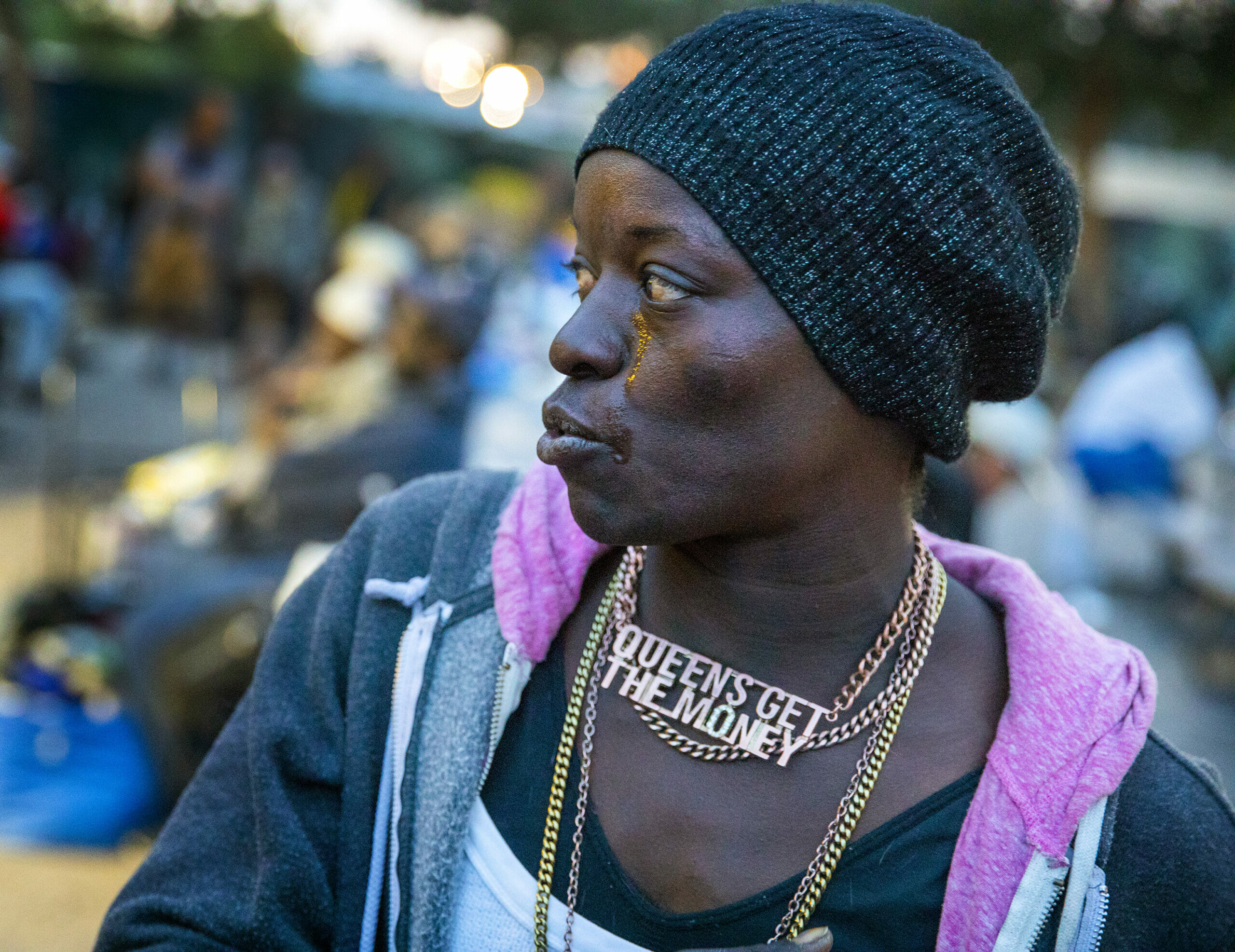 Kenya Obote wearing a light jacket, gold necklaces and a black scarf on her head