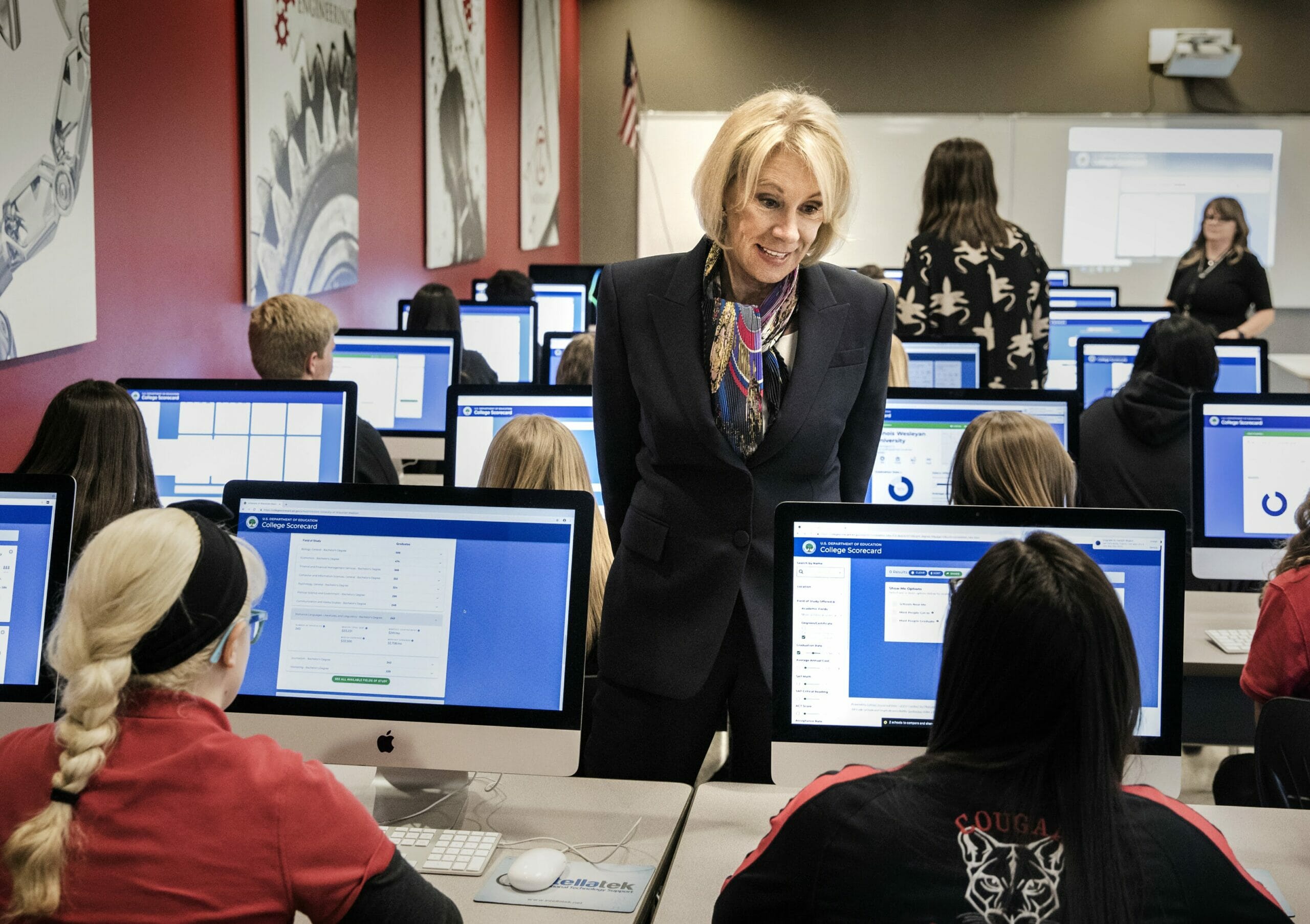 Betsy DeVos speaking with a student seated in front of a computer