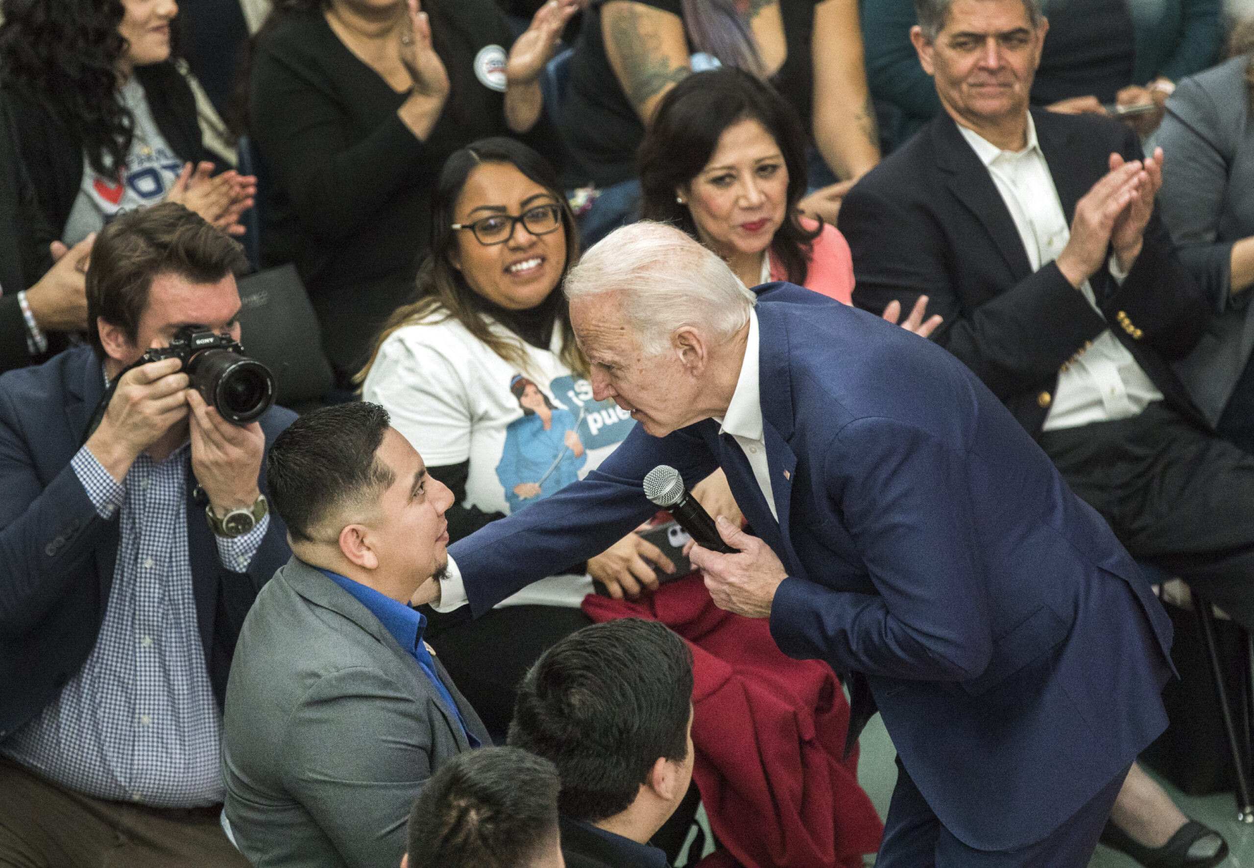 Joe Biden speaking with a man seated in the crowd during an event