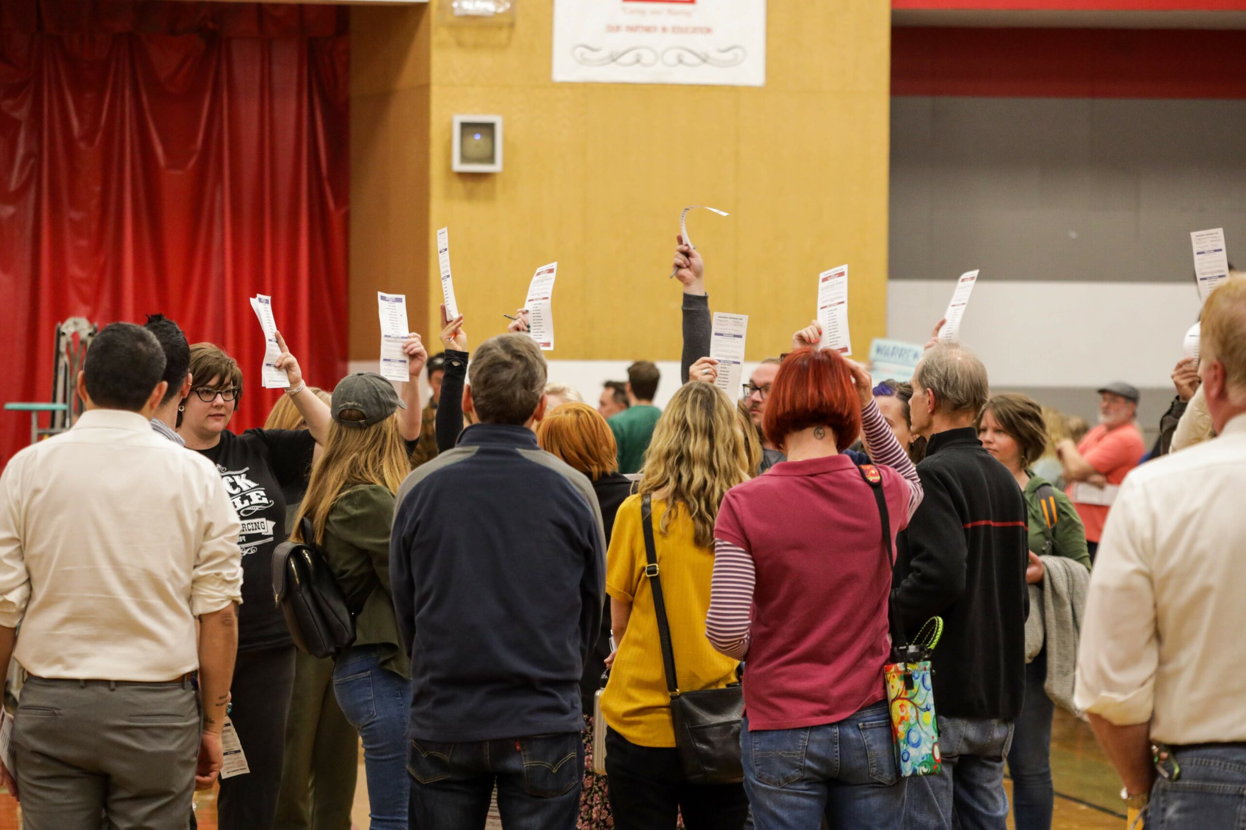 Caucusgoers holding up ballots at Wooster High School in Reno