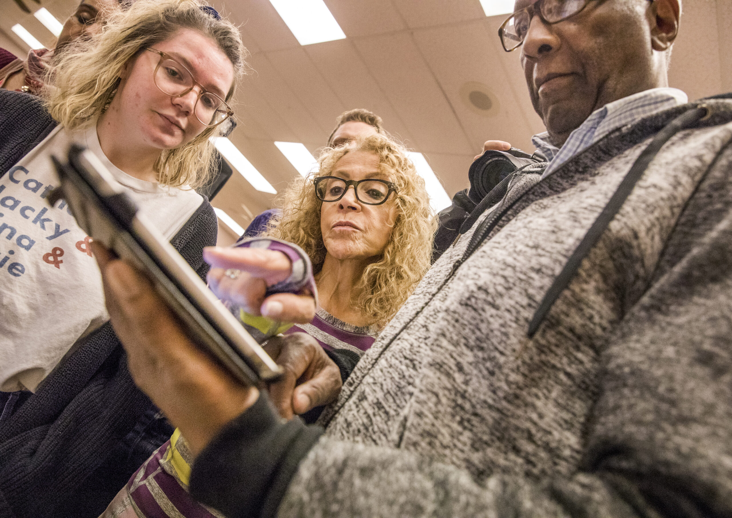 Digital director Emma Kraus, left, assists volunteers Diane and James Richmond during a caucus training