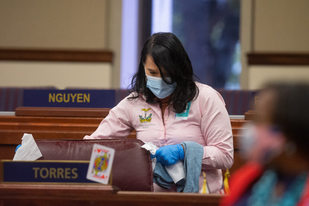 A member of the Legislative janitorial staff cleans inside the Assembly chambers on Friday, July 31, 2020 during the first day of the 32nd Special Session of the Legislature in Carson City.