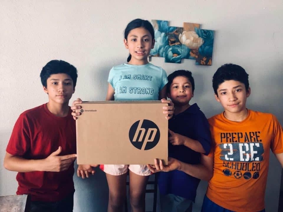 Camila Flores, 11, and her brothers clutch a new laptop that was donated to their family ahead of the upcoming school year.