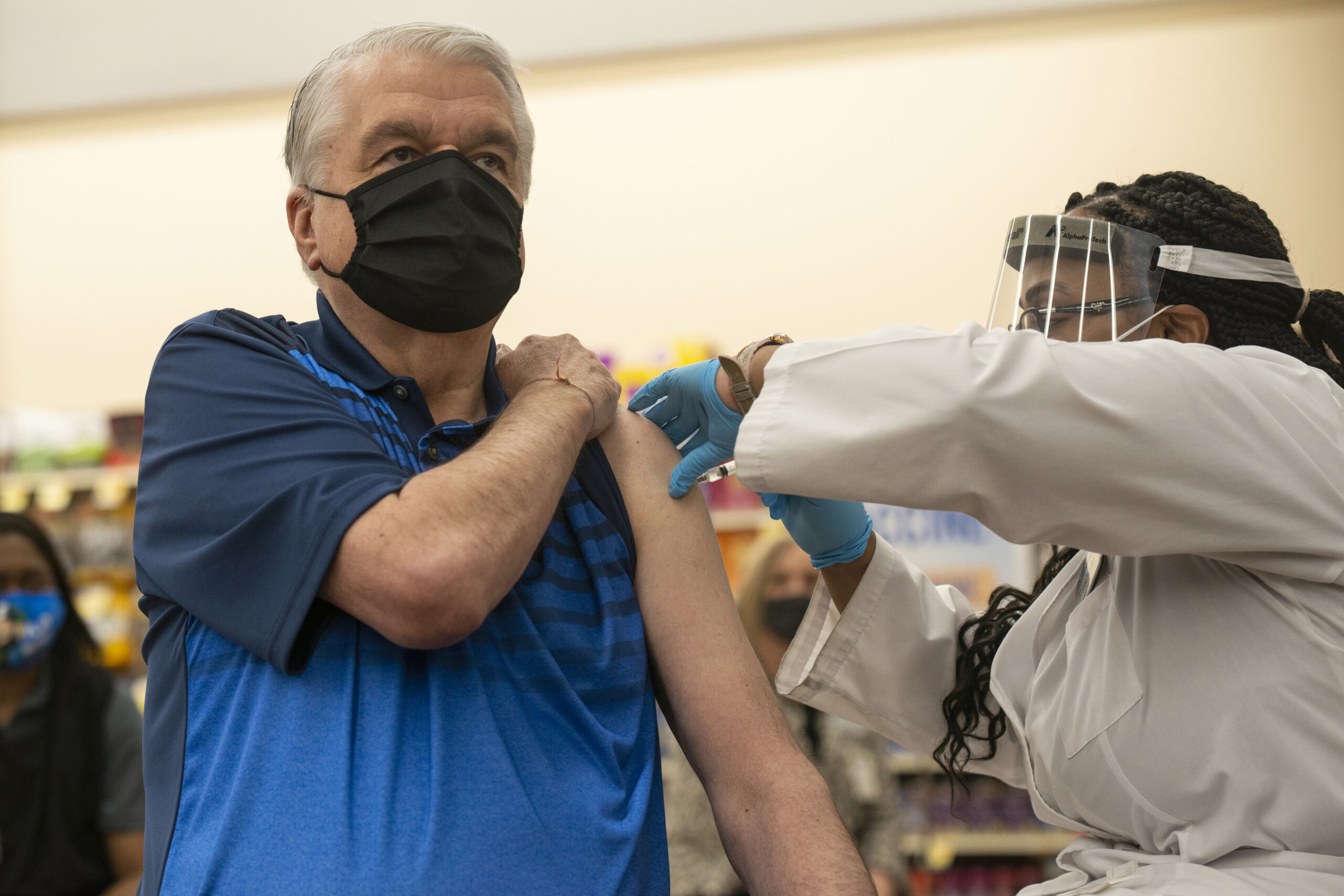 Steve Sisolak receives the COVID-19 vaccine from an Albertsons pharmacist