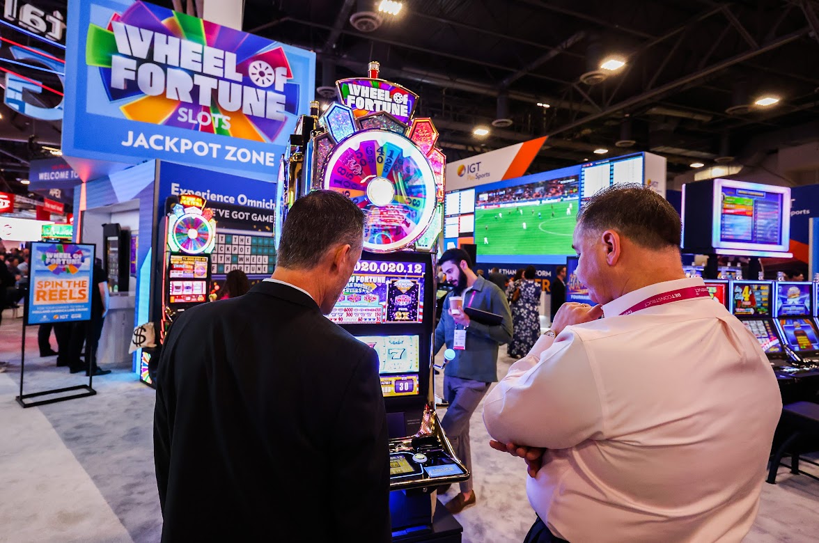 Global Gaming Expo attendees discuss a Wheel of Fortune slot machine at the IGT booth during the tradeshow on Oct. 11, 2022. (Jeff Scheid/The Nevada Independent).