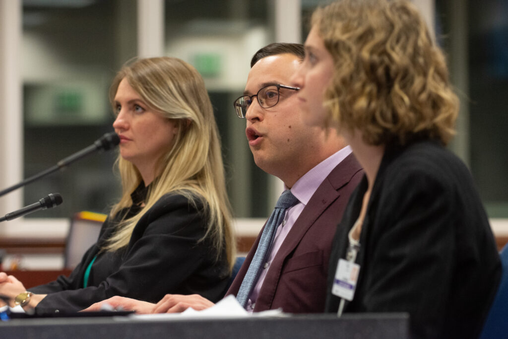 Erik Jimenez, center, chief policy deputy in the State Treasurer's office, presents SB 315 during a Senate Health and Human Services Committee hearing along with Sen. Melanie Scheible (D-Las Vegas), left and Scheible's legislative intern, Erin Shaffer, right, on April 4, 2023, at the Legislature in Carson City. (David Calvert/The Nevada Independent)