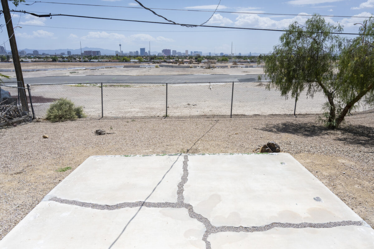 Cracked pavement and a view of the Las Vegas Strip from Nancy Johnson's backyard in the Windsor Park neighborhood in North Las Vegas on Wednesday, May 10, 2023. (Daniel Clark/The Nevada Independent).