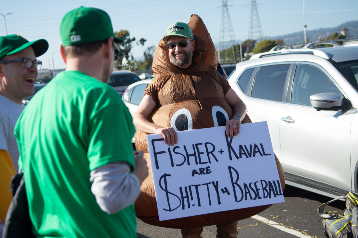 A fan holds a sign protesting A's owner John Fisher and President David Kaval outside the Oakland Coliseum in Oakland, Calif., on Friday, May 12, 2023. (David Calvert/The Nevada Independent).