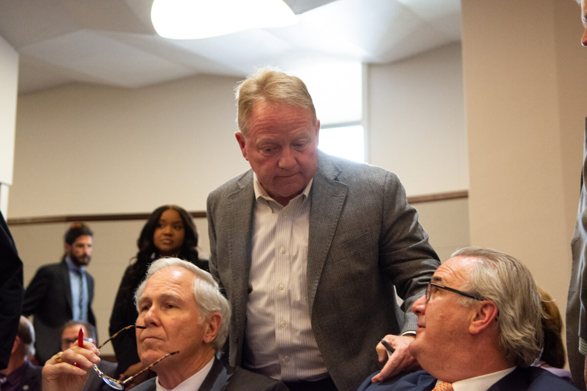 Tom Burns, executive director of the Nevada Governor's Office of Economic Development speaks with lobbyist Greg Ferraro, right, and Brandon Birtcher, left, co-owner and CEO of Birtcher Development, during a hearing for SB496 inside the Legislature in Carson City on Tuesday, May 16, 2023. (David Calvert/The Nevada Independent)