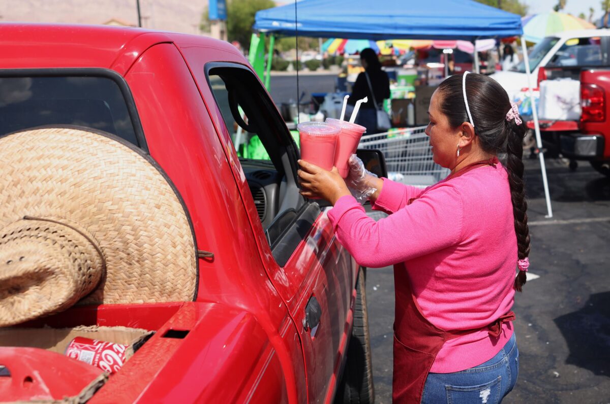 Street vendor Maribel Rojas Flores delivers drinks to a costumer at her stand in East Las Vegas on Tuesday, June 13, 2023. (Jeff Scheid/The Nevada Independent)