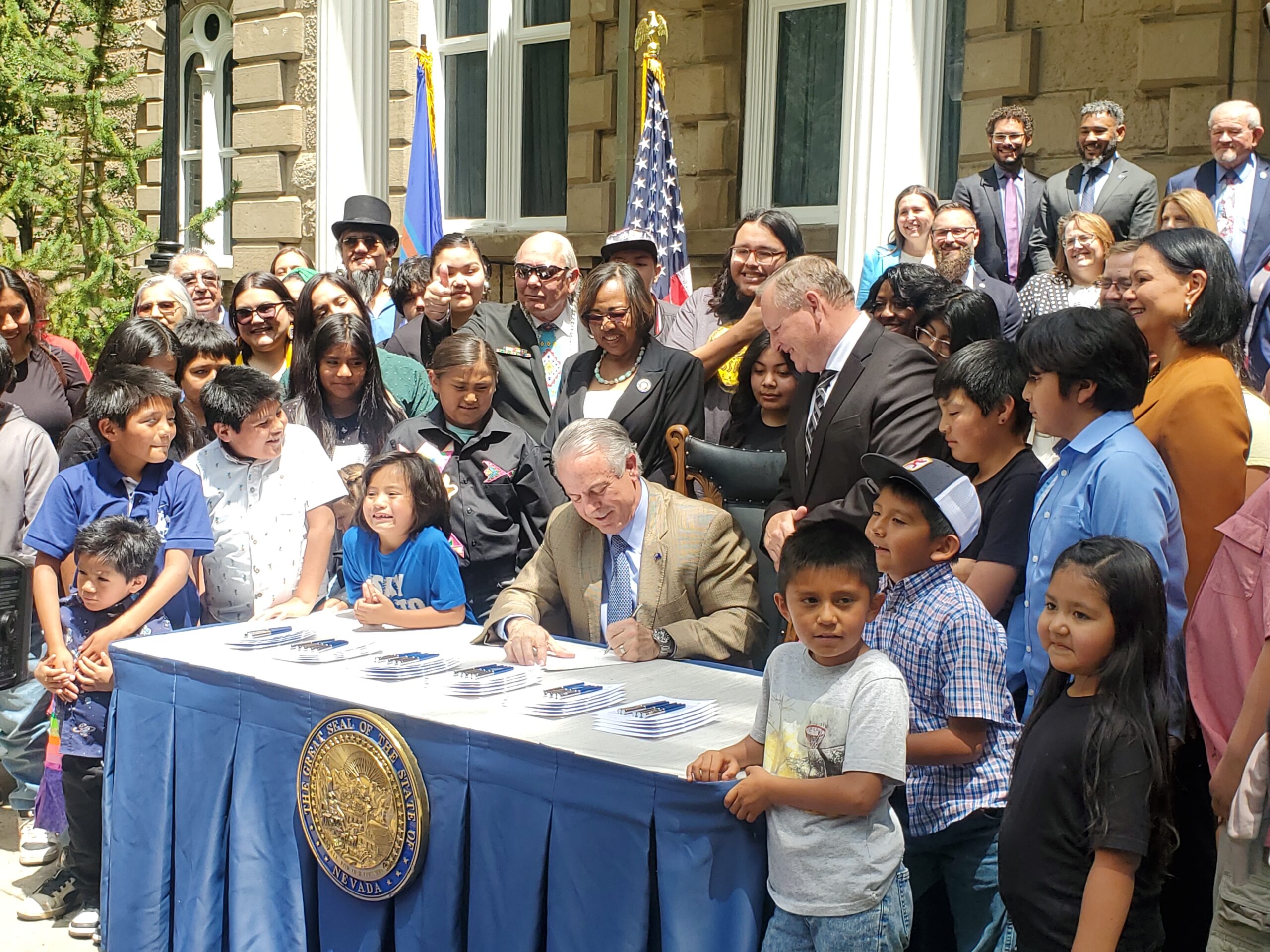 Gov. Joe Lombardo signs AB519, a bill that provides almost $65 million for a new school on the Duck Valley Indian Reservation, surrounded by Owyhee residents, legislators and educators on Tuesday, June 13, 2023 in Carson City. (Carly Sauvageau/The Nevada Independent).