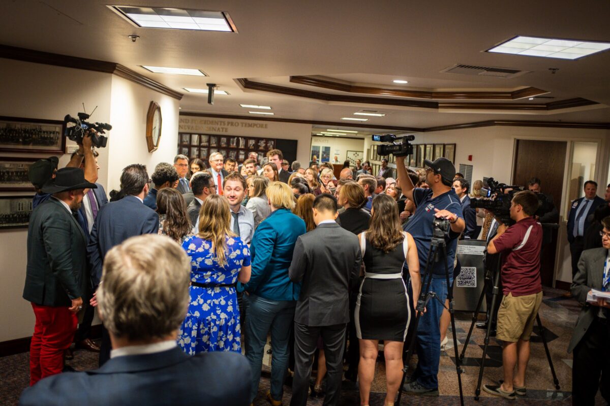 Lawmakers meeting in a hallway during a conference committee surrounded by reporters and lobbyists on the final day of the regular legislative session, June 5, 2023, in Carson City. (Joey Lovato/The Nevada Independent).