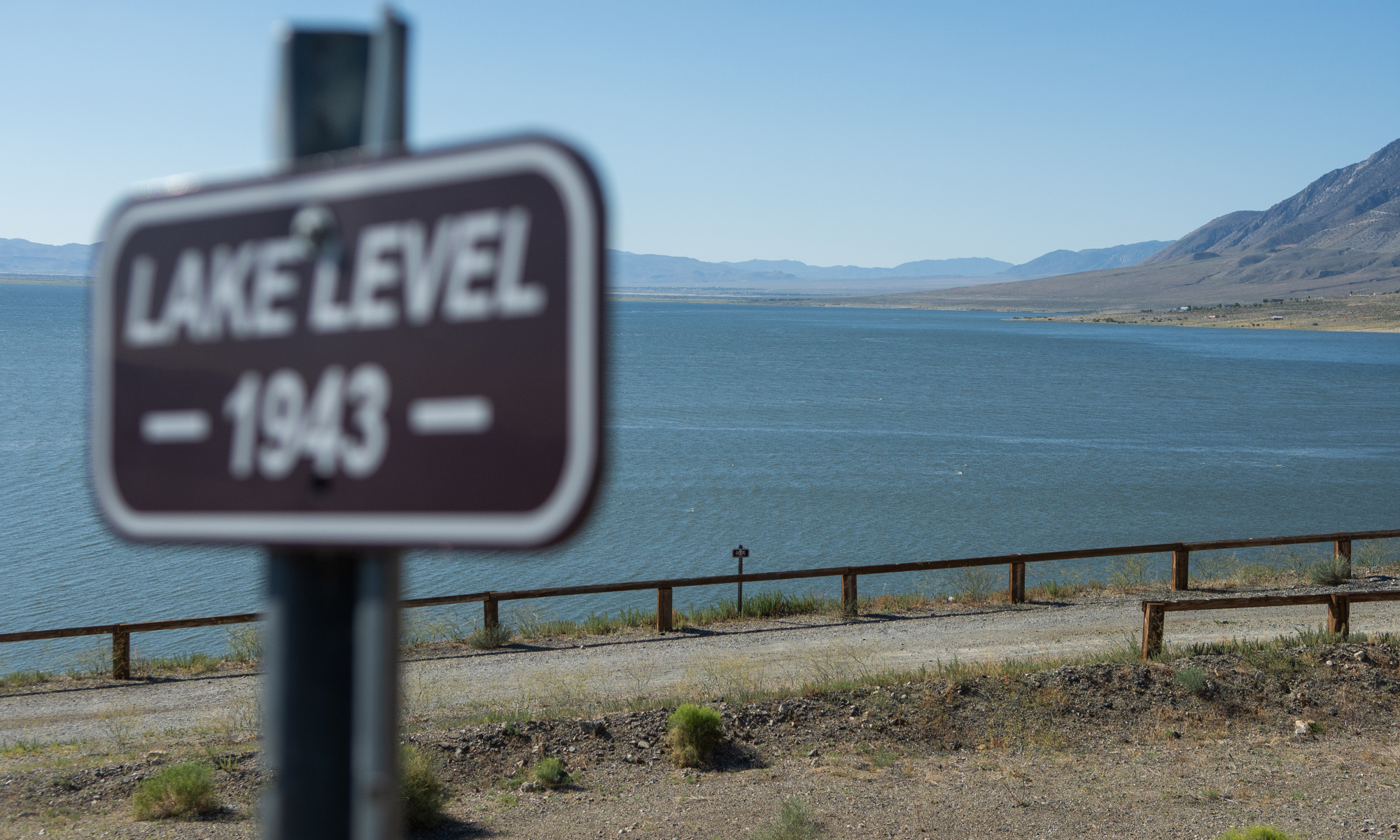 A sign installed by the Walker Lake Working Group marking the water level in 1943 at Sportsman’s Beach at Walker Lake on June 22, 2023, near Hawthorne. The sign behind it shows the drop in water level less than a decade later, in 1951. (David Calvert/The Nevada Independent).