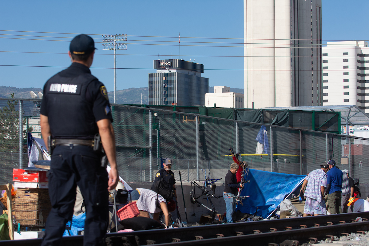 Reno Police officers and members of the city's Clean and Safe Field Team during a clean up of a camp along the train tracks between Record Street and the Wells Avenue overpass in Reno on July 18, 2023. (David Calvert/The Nevada Independent)
