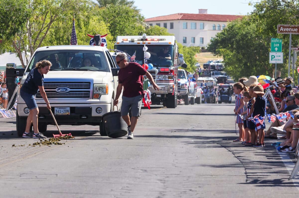 A couple picks up horse poop during the 75th annual Damboree parade in Boulder City on Tuesday, July 4, 2023. (Jeff Scheid/The Nevada Independent)