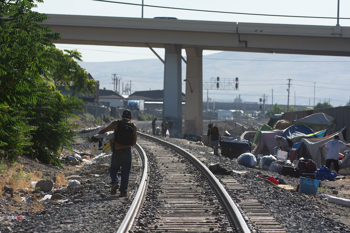 Unhoused community members pack their belongings ahead of a clean up of a camp along the train tracks between Record Street and the Wells Avenue overpass in Reno on July 18, 2023. (David Calvert/The Nevada Independent)