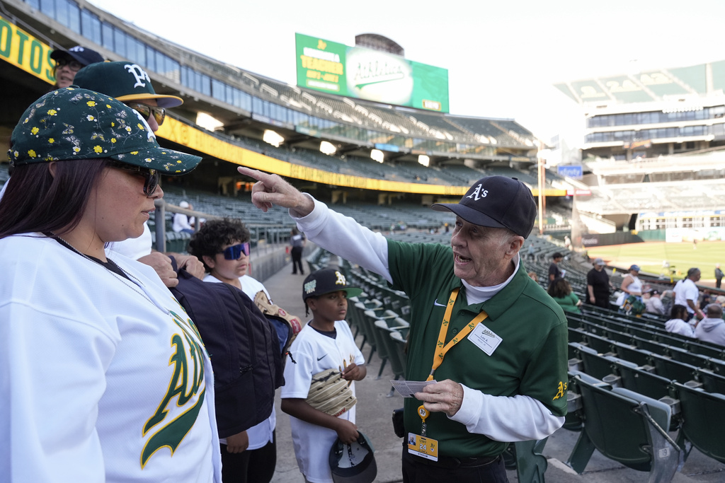 Leland Anderson, right, speaks with fans attending a baseball game between the Colorado Rockies and the Oakland Athletics.