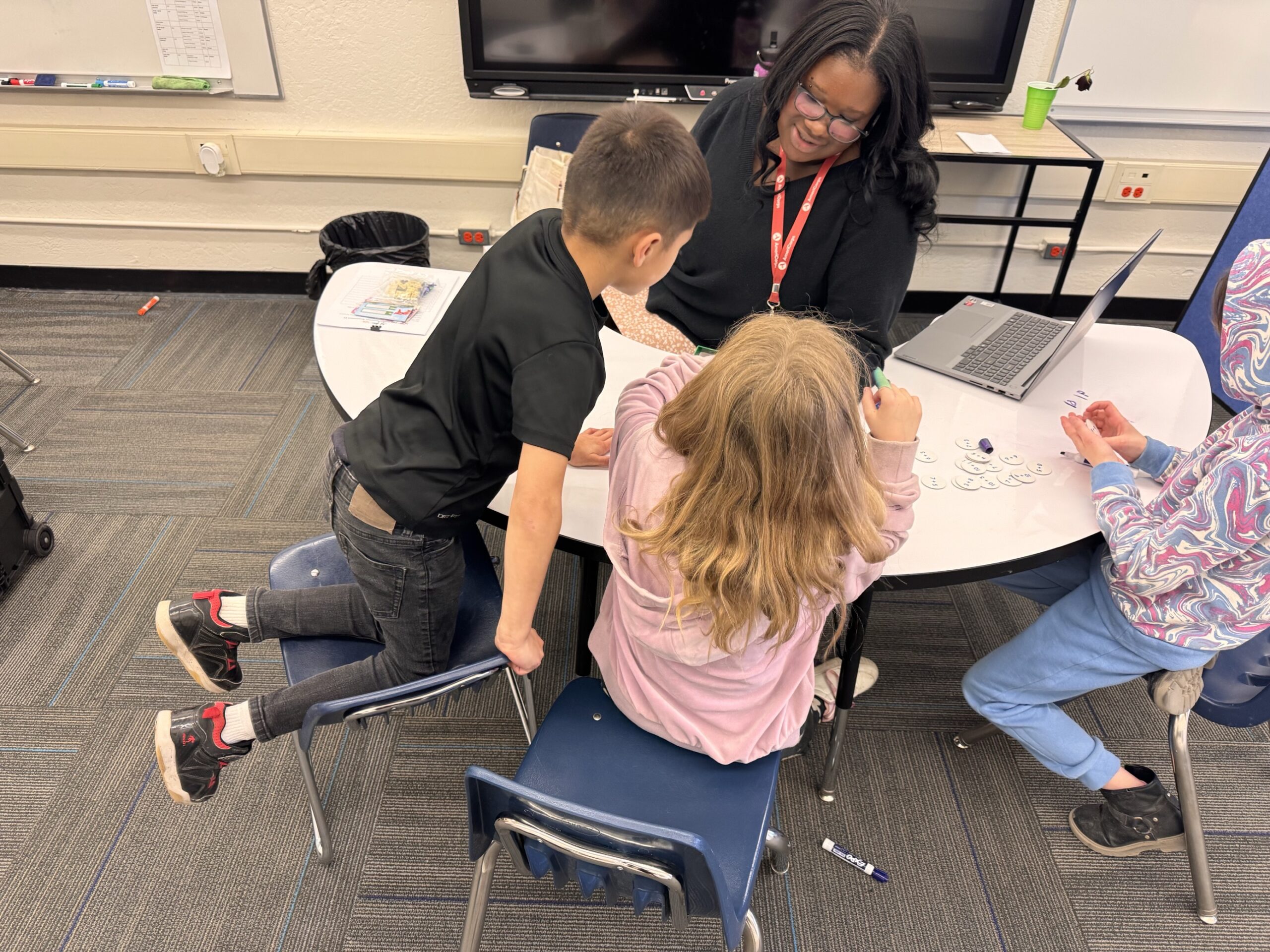 An AmeriCorps member works as a mentor with elementary school students.