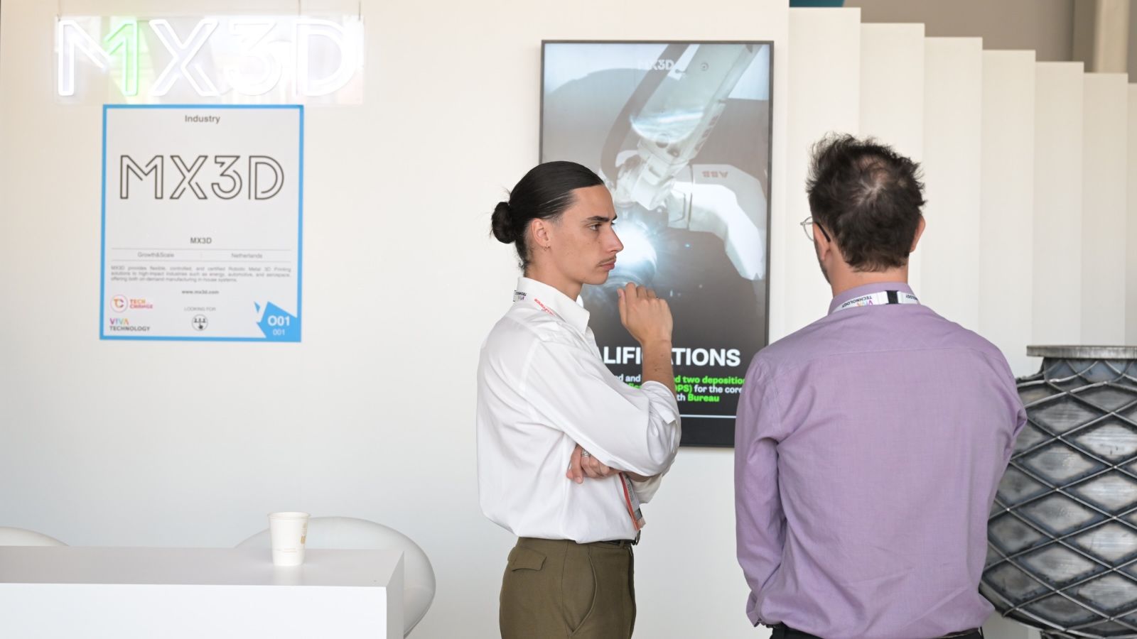 two men talking in front of a startup booth