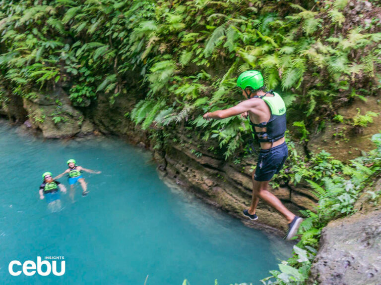 A tourist jumps into the crystal clear waters during the Badian Canyoneering adventure